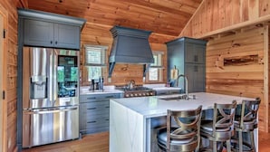 Una cocina moderna con electrodomésticos de acero inoxidable, una isla central con taburetes de bar y paneles de madera.