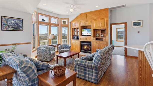 A spacious living room with a fireplace, large windows, and a cozy seating area. - Despacito: Pool, Hot Tub, Walk to Beach OBX (Corolla)