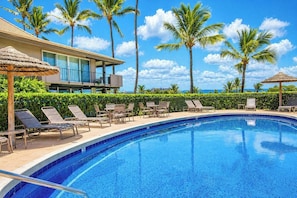A swimming pool with lounge chairs, palm trees, and a building with a balcony. - KBM Resorts | FREE CAR | Maui El Dorado |Ocean view | 1-Bedroom Condo! MEL-H207 (Lahaina)