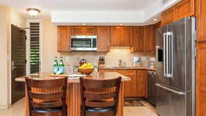 Een moderne keuken met houten kastjes, roestvrijstalen apparatuur en een centraal eiland met twee stoelen.