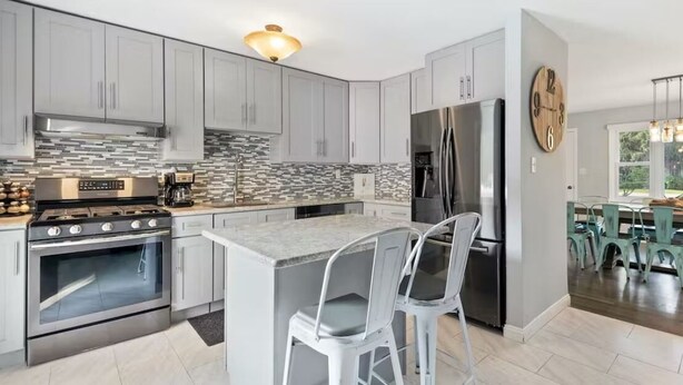 A modern kitchen with grey cabinets, a stainless steel refrigerator, and a built-in oven.