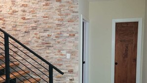 A staircase with a wooden handrail and a stone wall.