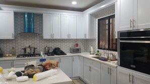 A kitchen with white cabinets, a stainless steel stove, a black oven, and a window with a metal grid.