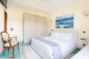A bedroom with a bed, a chair, a wardrobe, and a painting of a sailboat on the wall. - Family Home with terrace & view in Sorrento Center (Sorrento)