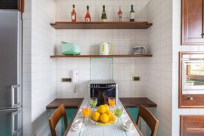 A kitchen with a dining table set for two, a refrigerator, a coffee maker, and a microwave. - Family Home with terrace & view in Sorrento Center (Sorrento)