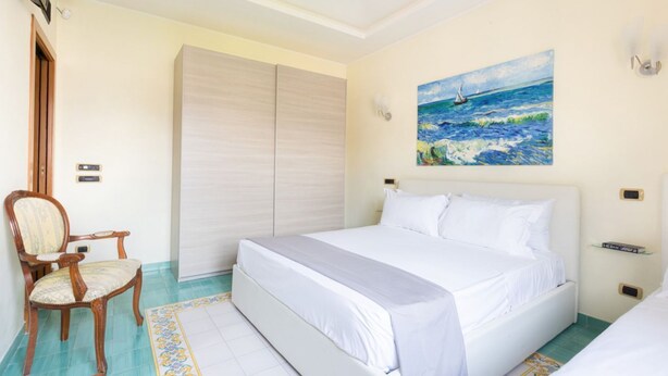 Un dormitorio con cama, una silla, un armario y un cuadro de un velero en la pared.