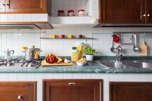 A kitchen with wooden cabinets, a gas stove, a sink, and various kitchen items on the countertop. - Family Home with terrace & view in Sorrento Center (Sorrento)
