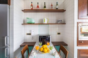 A kitchen with a dining table set for two, a refrigerator, a coffee maker, and a microwave. - Family Home with terrace & view in Sorrento Center (Sorrento)