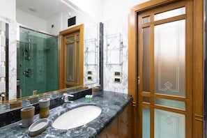 A modern bathroom with a marble sink, glass shower enclosure, and wooden doors. - Family Home with terrace & view in Sorrento Center (Sorrento)