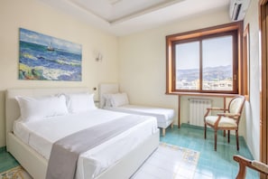 A bedroom with a large bed, two single beds, a chair, a painting of a seascape, and a window with a city view. - Family Home with terrace & view in Sorrento Center (Sorrento)