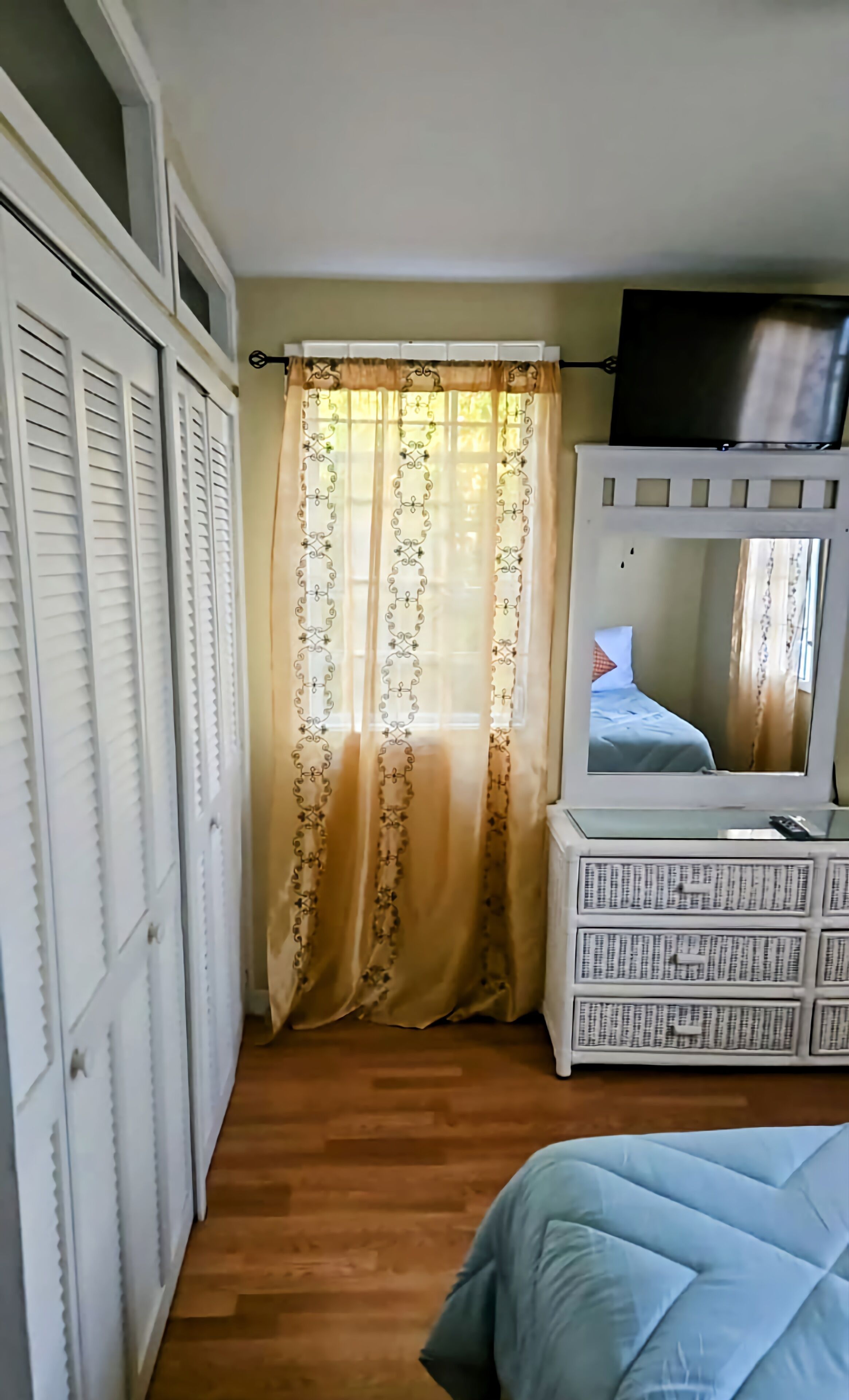 Une chambre à coucher avec un lit, une commode, un miroir et une armoire.