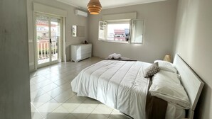 Une chambre à coucher avec un lit, une commode, une fenêtre et un balcon.