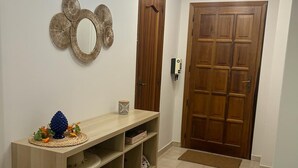 Un couloir avec une console en bois, un miroir et deux portes en bois.