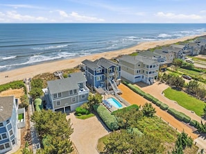 Zona residencial costera con casas, piscina y playa.