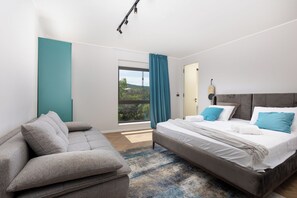 Relax in a serene space with a large bed, sofa, and stunning views of the surrounding greenery.