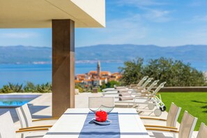 Enjoy a romantic dinner for two under a scenic structure with a view of the water and distant town.