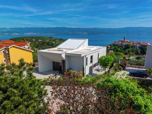 Situated in a lush, green area, this property offers a serene environment with a clear view of the sea and distant mountains.