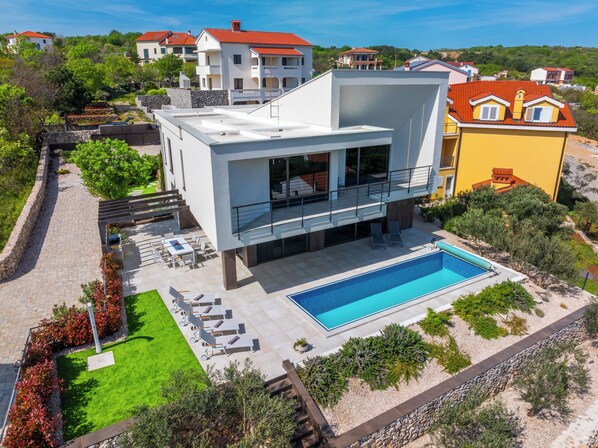 Relax in a serene outdoor setting with a swimming pool, garden, and patio seating.