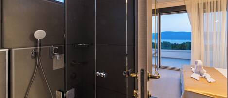 A modern hotel room with a shower, a bed with a view, and a large window.