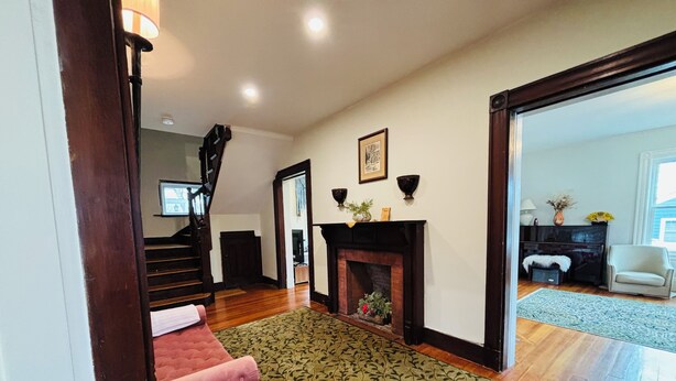 A spacious living room with a fireplace, a staircase, and a view into another room.