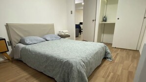 Et soveværelse med en seng, et natbord, et klædeskab og et spejl.