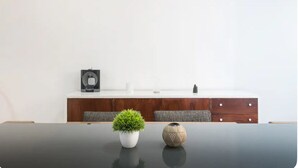 Et moderne værelse med et mørkt træbord, en hvid vase med en grøn plante og et dekorativt keramikstykke.
