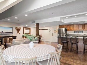 A modern kitchen with a stainless steel refrigerator, wooden cabinets, and a bar area.