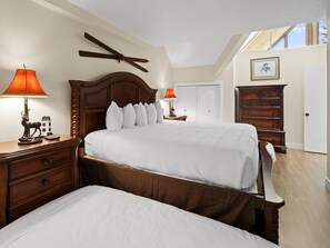 A bedroom with a large bed, two nightstands with lamps, a dresser, and a ceiling fan.