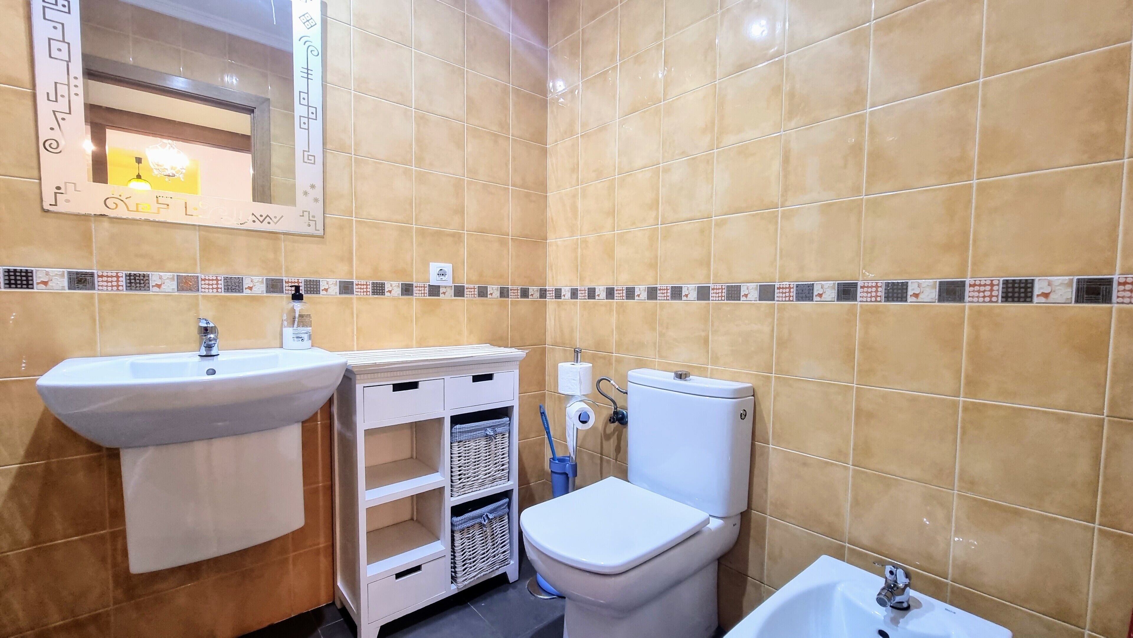 Ein Badezimmer mit beigen Fliesen, einem Waschbecken, einer Toilette und einem Bidet.