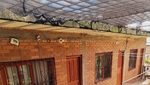 A brick building with barred windows, a wooden door, and a metal staircase. - Valeria  (Puerto Iguazú)