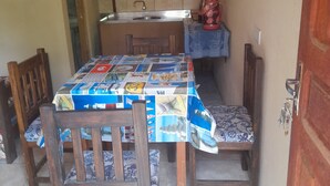 A compact kitchen with a tiled backsplash, a sink, and a countertop. There is a table with a patterned tablecloth and wooden chairs. - Valeria  (Puerto Iguazú)