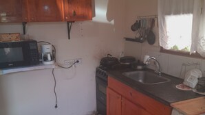 A compact kitchen with wooden cabinets, a microwave, a coffee maker, a stove, and a sink. - Valeria  (Puerto Iguazú)