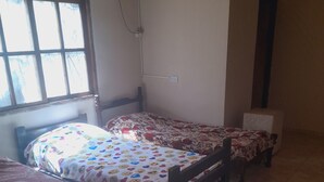 A room with three wooden beds, a window with blinds, an air conditioning unit, and a tiled floor. - Valeria  (Puerto Iguazú)