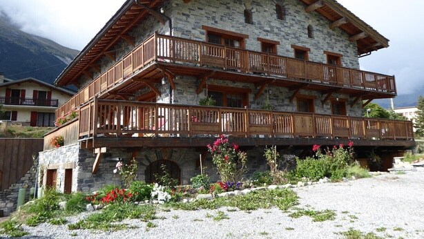 A multi-story stone building with wooden balconies and a gravel driveway. - Apartment 'L'erelaz' with Mountain View and Wi-Fi (SOLLIERES SARDIERES)