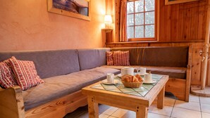 A cozy room with a wooden sofa, a small table with a basket of bread, and a window with curtains. - Apartment 'L'erelaz' with Mountain View and Wi-Fi (SOLLIERES SARDIERES)