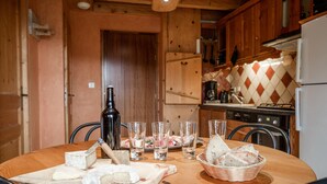 A wooden interior with a dining table set for a meal, featuring cheese, bread, and glasses. - Apartment 'Les Mélèzes' with Mountain View, Balcony and Wi-Fi (SOLLIERES SARDIERES)