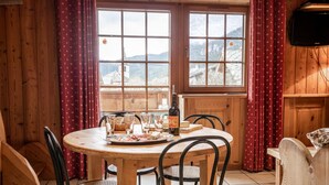 A wooden dining table with chairs, a bottle, glasses, and a cheese board. - Apartment 'Les Mélèzes' with Mountain View, Balcony and Wi-Fi (SOLLIERES SARDIERES)