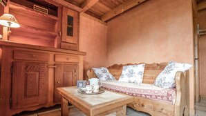 A wooden room with a sofa, a table with a tray of mugs, and a lamp. - Apartment 'Les Mélèzes' with Mountain View, Balcony and Wi-Fi (SOLLIERES SARDIERES)
