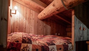 A wooden cabin interior with a bed, wooden walls, a sloped ceiling, and a light fixture. - Apartment 'Le Monolithe' with Mountain View, Balcony and Wi-Fi (SOLLIERES SARDIERES)