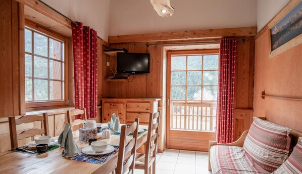Eine Holzhütte mit Esstisch, Stühlen, Fernseher und einer Couch.