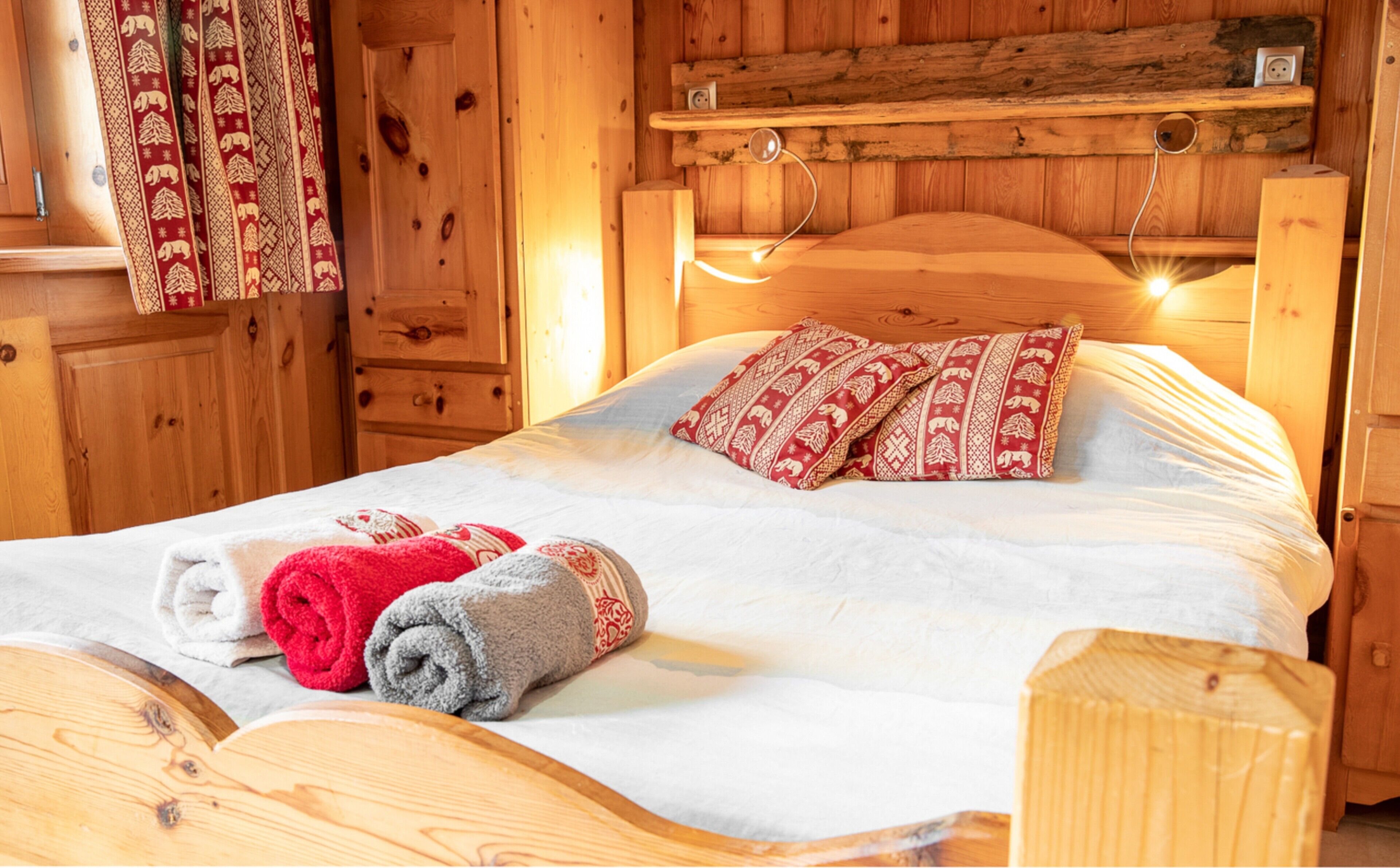 Une pièce en bois avec un lit, une commode en bois et une étagère fixée au mur.