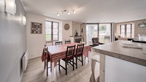 A dining area with a wooden table and chairs, a kitchen counter, and a view of the outdoors.