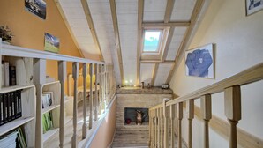A wooden staircase with a skylight, bookshelves, and a framed picture.