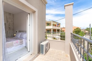 A balcony with a bed, a radiator, and a view of neighboring buildings.