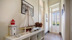 Ein Flur mit einer weißen Konsole, auf der ein Modellsegelboot, ein Leuchtturm und ein gerahmtes Foto ausgestellt sind.
