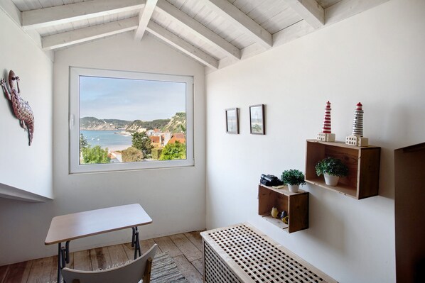 A room with a large window, a desk, a radiator, and wooden shelves with decorative items.