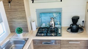 A modern kitchen with a Bosch dishwasher, a gas stove, a coffee maker, and a small potted plant. - Chalet 'Strandliebe Bredene' with Private Terrace (Bredene)