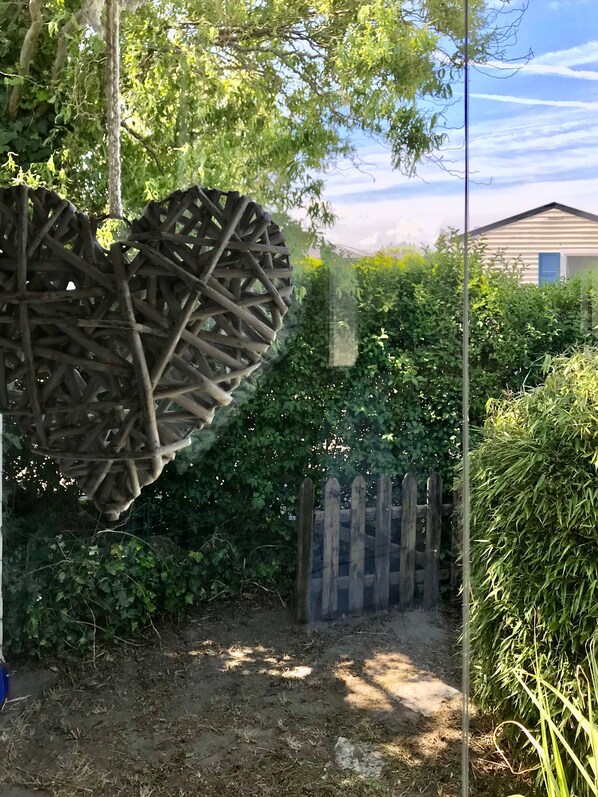 A garden with a heart-shaped wooden structure, a wooden fence, and dense foliage. - Chalet 'Strandliebe Bredene' with Private Terrace (Bredene)