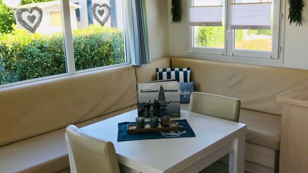 A cozy room with a white table, beige chairs, a bench, and a window with blinds. - Chalet 'Strandliebe Bredene' with Private Terrace (Bredene)