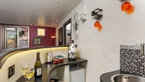 A modern kitchen with a built-in coffee machine, a mini-fridge, and two wine glasses on the counter. - Tao Rama Suite Apartment with Sea View, Wi-Fi, and Air Conditioning (Taormina)